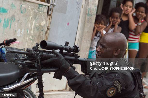 Group of girls watch how a PM paramilitary police BOPE special unit sniper secures the area as Brazilian soldiers conduct a search for weapons in the...