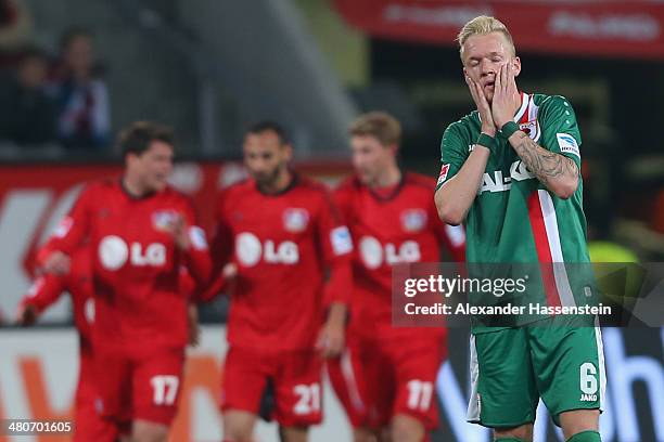 Kevin Vogt of Augsburg reacts whilst players of Leverkusen celebrate their 3rd team goal during the Bundesliga match between FC Augsburg and Bayer...