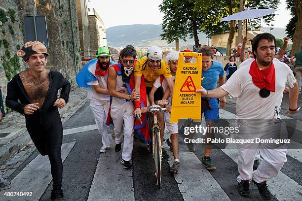 Revellers run with a cyclist depicting 'Miguel Indurain' during the Villavesa running after the San Fermin festival finished on July 15, 2015 in...