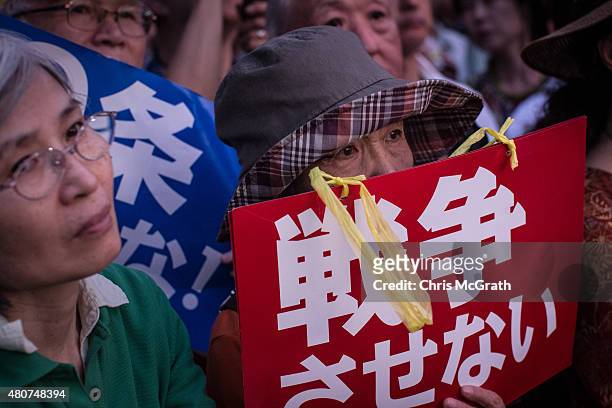 Woman holds a sign during a protest outside the National Diet on July 15, 2015 in Tokyo, Japan. Protesters gathered after the ruling Liberal...