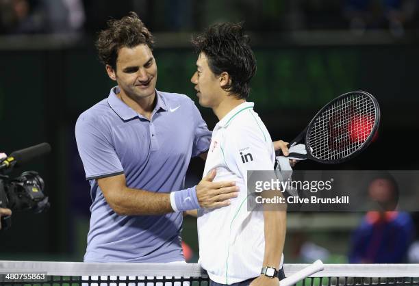 Roger Federer of Switzerland at the net after his three set defeat congratulates Kei Nishikori of Japan during their quarter final round match during...