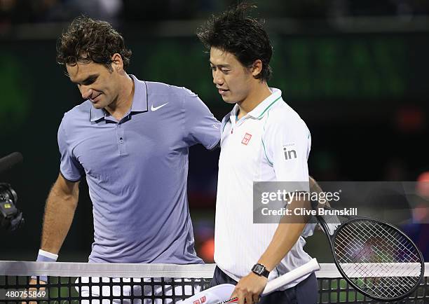 Roger Federer of Switzerland at the net after his three set defeat congratulates Kei Nishikori of Japan during their quarter final round match during...