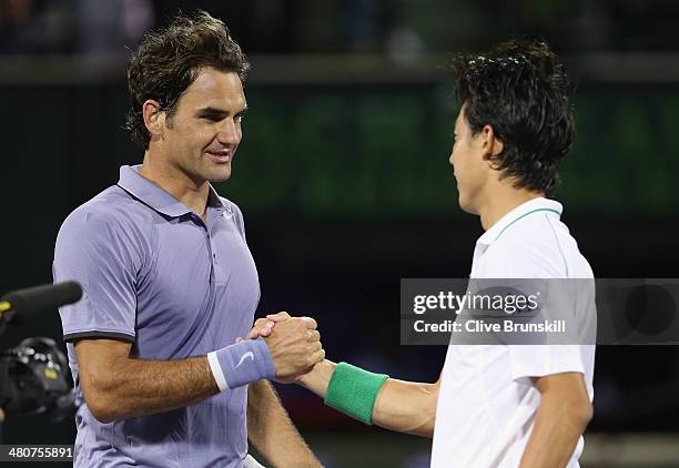 Roger Federer of Switzerland shakes hands at the net after his three set defeat by Kei Nishikori of Japan during their quarter final round match...