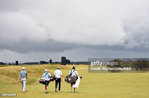 Jordan Spieth of the United States and Brooks Koepka walk up a fairway with their caddies ahead of the 144th Open Championship at The Old Course on...