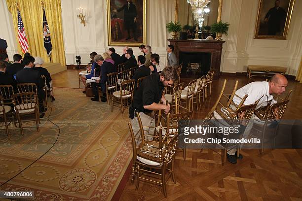 White House empoyees remove unoccupied chairs from the East Room ahead of U.S. President Barack Obama's news conference July 15, 2015 in Washington,...