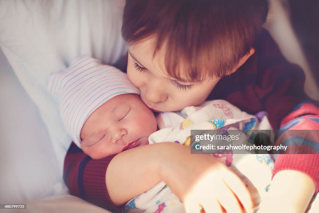 Child kissing newborn in hospital