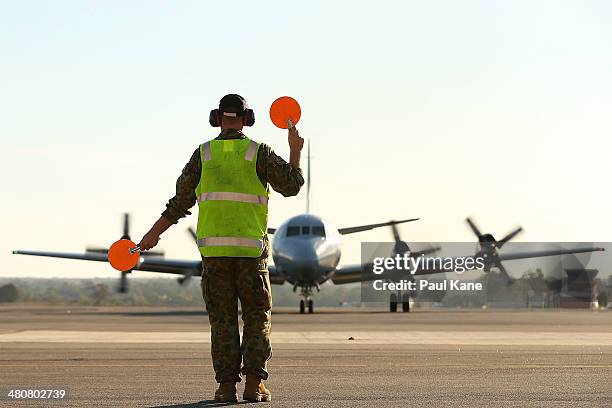 An RAAF signalman directs an AP-3C Orion for parking on the apron after returning from a search mission for MH370 debris at RAAF Base Pearce on March...