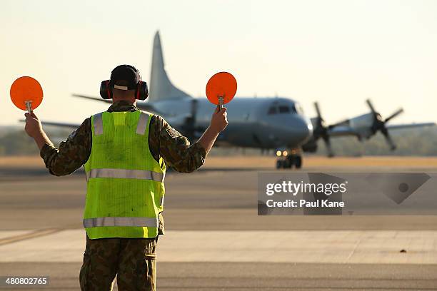 An RAAF signalman directs an AP-3C Orion for parking on the apron after returning from a search mission for MH370 debris at RAAF Base Pearce on March...