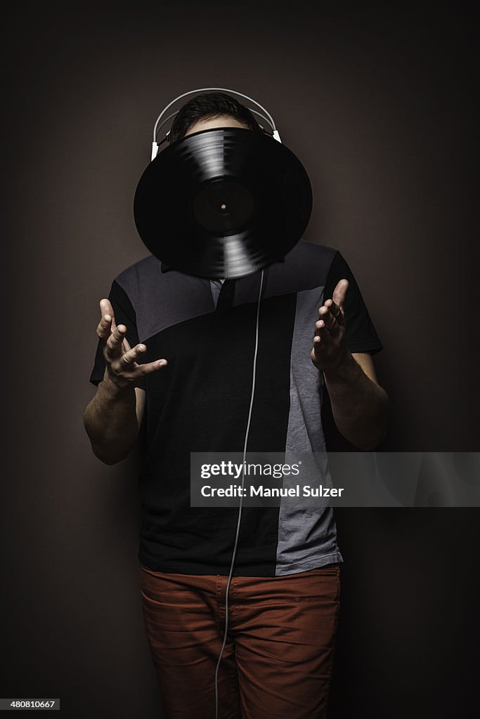 Young man wearing headphones throwing vinyl record