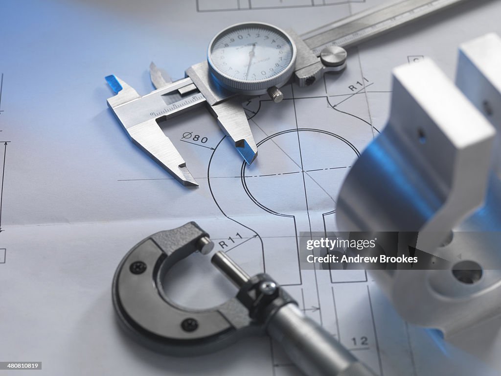 Engineering drawing with product, micrometer and calipers