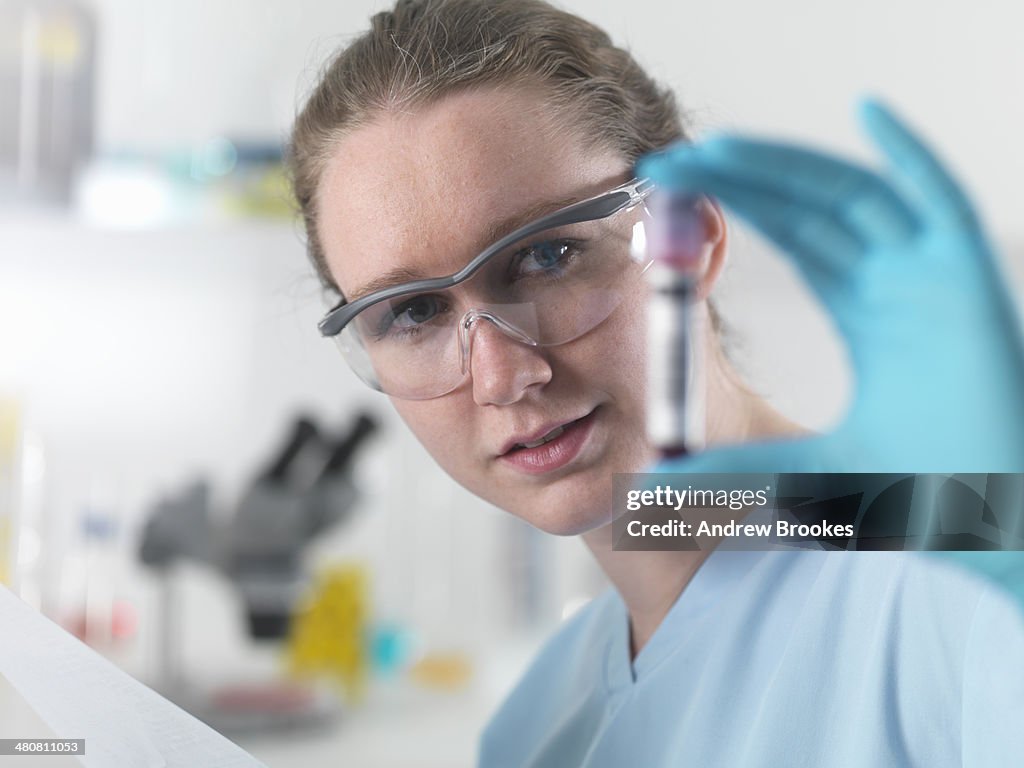 Technician holding bar coded blood sample in clinical laboratory