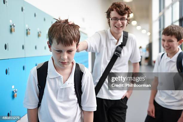 schoolboy being bullied in school corridor - bullying children stock pictures, royalty-free photos & images