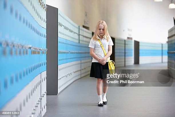 unhappy schoolgirl walking alone in school corridor - schoolgirl stock pictures, royalty-free photos & images