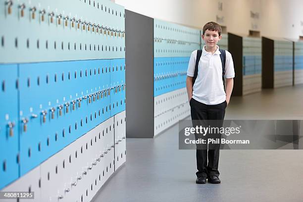 portrait of schoolboy with hands in pockets in school corridor - boy school uniform stock-fotos und bilder