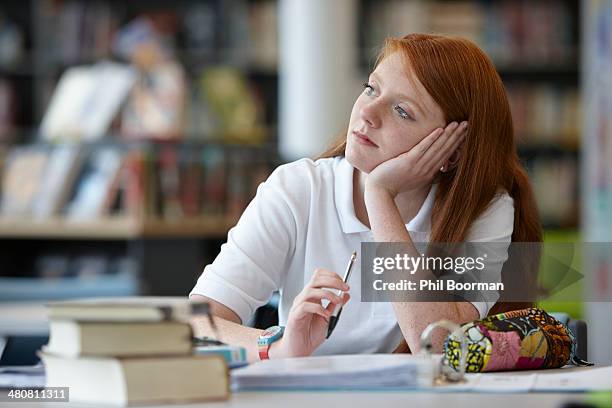portrait of teenage girl daydreaming in library - distraído imagens e fotografias de stock