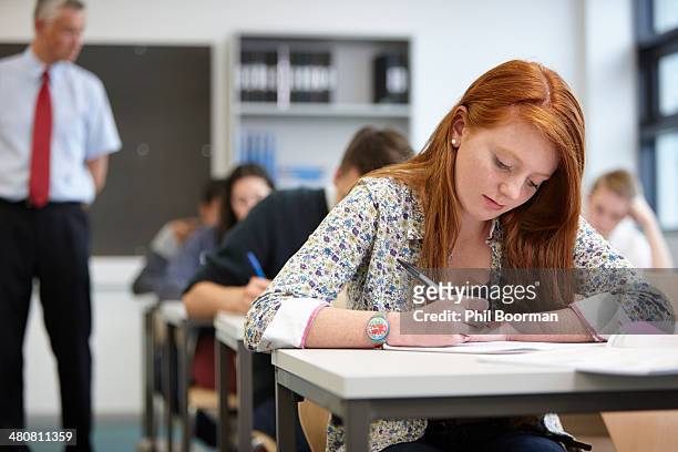 teacher watching over teenagers in classroom - school exam stockfoto's en -beelden