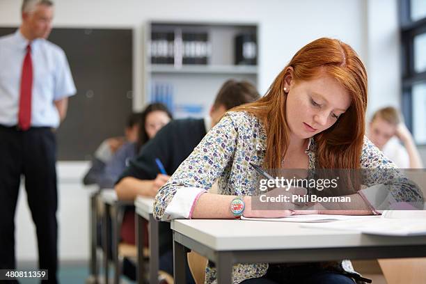 teacher watching over teenagers in classroom - school exam imagens e fotografias de stock