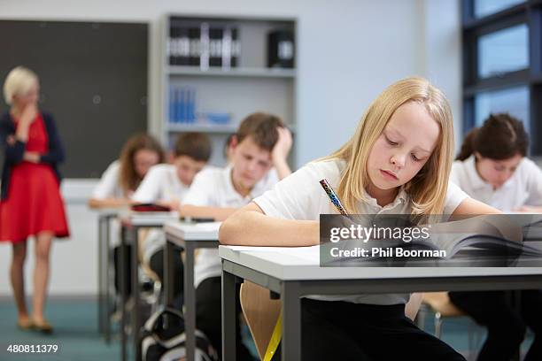 female teacher watching class doing educational exam - fachbuch stock-fotos und bilder