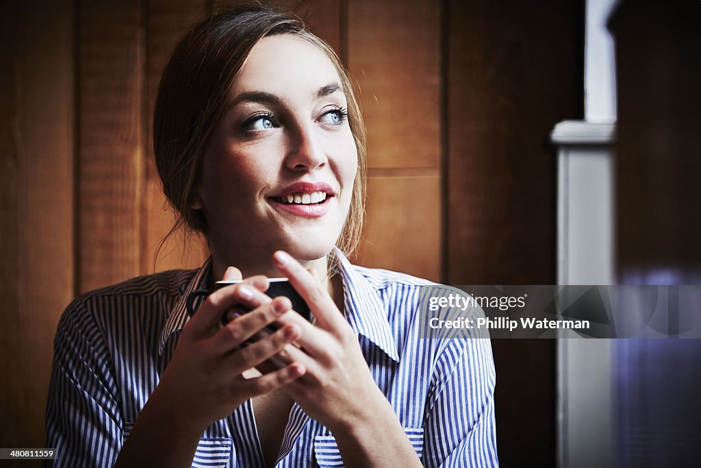 Young woman sitting in cafe holding hot drink