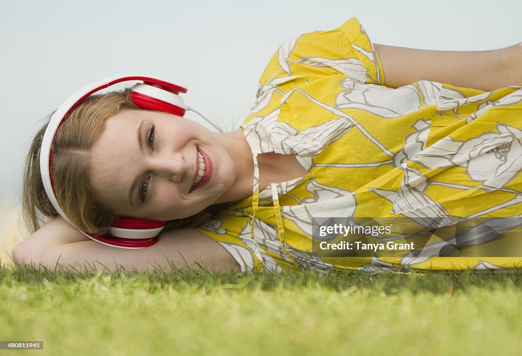 Portrait of young woman listening to headphones on grass