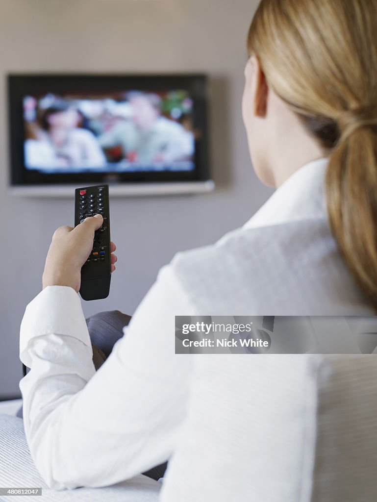 Young woman watching television in hotel room