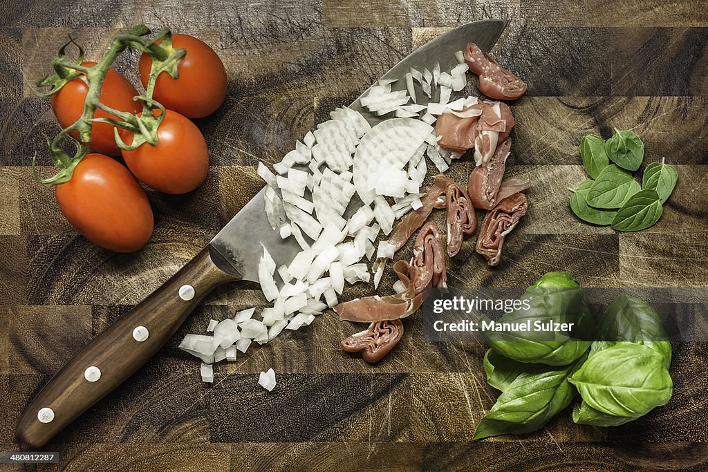 Still life of chopped onion and ham with tomatoes and herbs