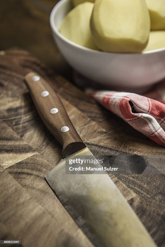 Still life of peeled potatoes in bowl and kitchen knife