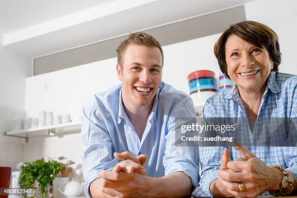 portrait of youthful grandmother with grandson in kitchen - leaning on elbows stock pictures, royalty-free photos & images