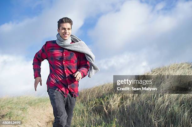 young man running on sand dunes, brean sands, somerset, england - sean malyon stock pictures, royalty-free photos & images