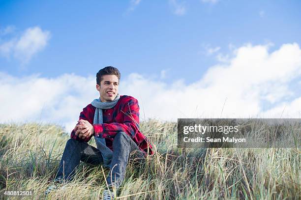 young man sitting on grass - sean malyon stock-fotos und bilder