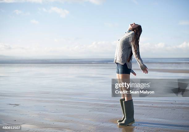 young woman standing on beach looking up, brean sands, somerset, england - sean malyon stockfoto's en -beelden