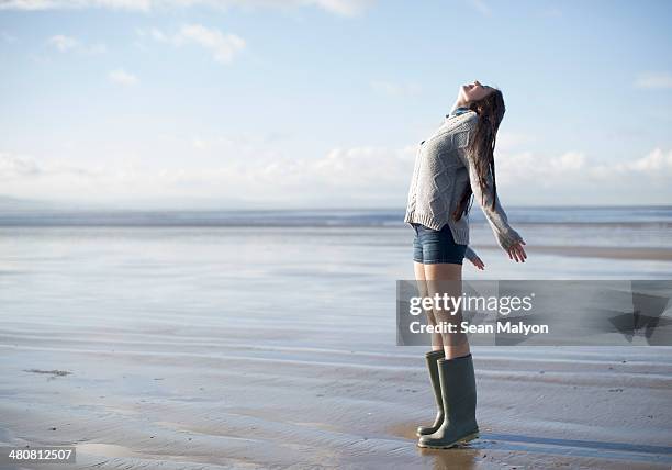 young woman standing on beach looking up, brean sands, somerset, england - sean malyon stock pictures, royalty-free photos & images