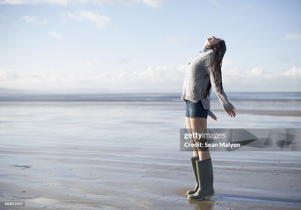 Young woman standing on beach looking up, Brean Sands, Somerset, England