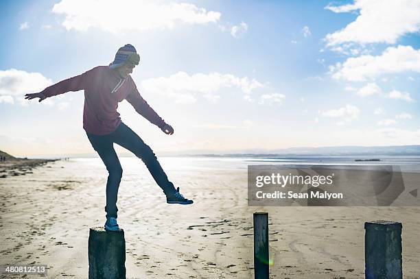 young man standing on groynes, brean sands, somerset, england - sean malyon stock-fotos und bilder