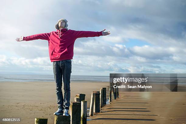 young man standing on groynes, brean sands, somerset, england - sean malyon stock-fotos und bilder