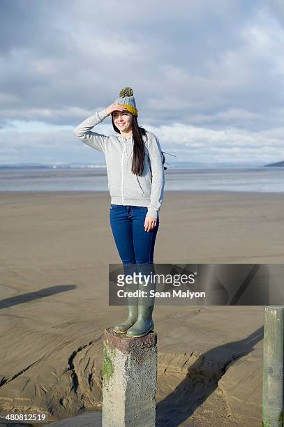 young woman standing on groynes, brean sands, somerset, england - sean malyon stockfoto's en -beelden