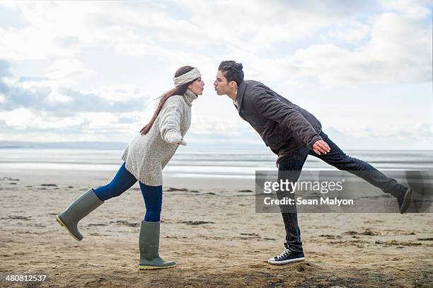 young couple on one leg, brean sands, somerset, england - sean malyon stockfoto's en -beelden