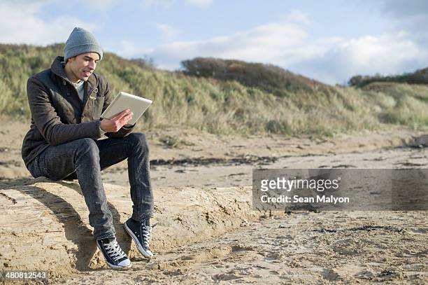 young man using digital tablet, brean sands, somerset, england - sean malyon stock-fotos und bilder