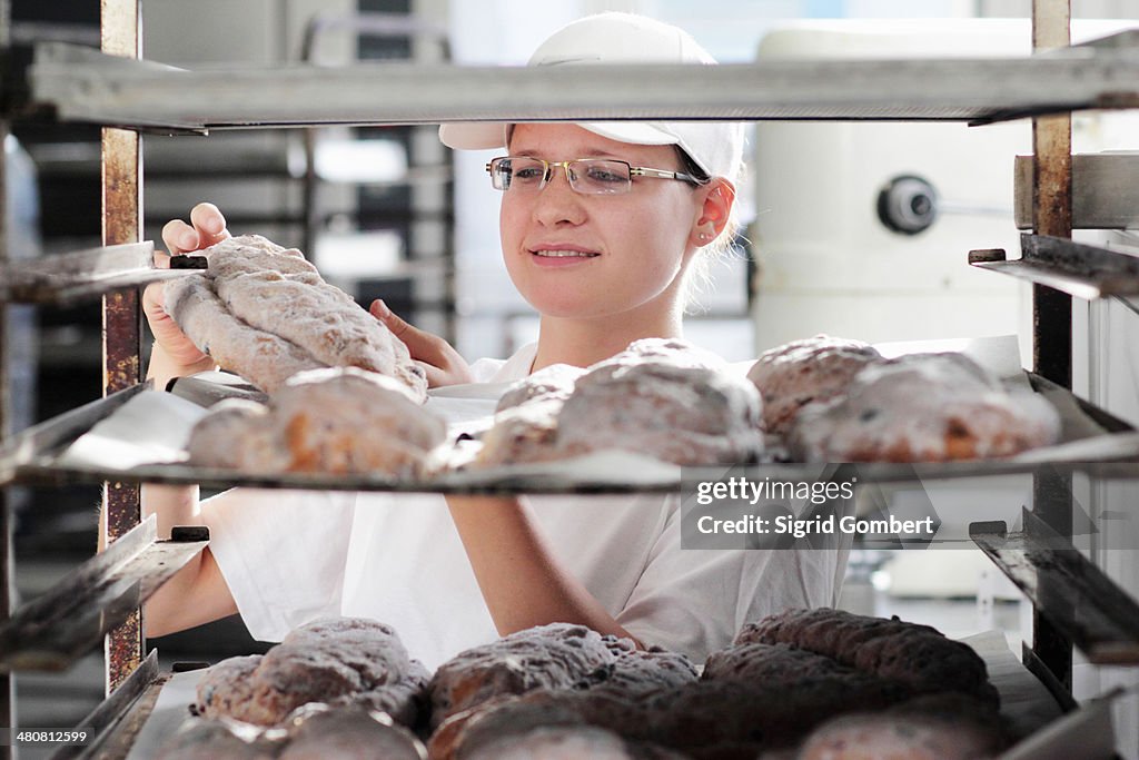 Baker putting bread dough on baking sheet
