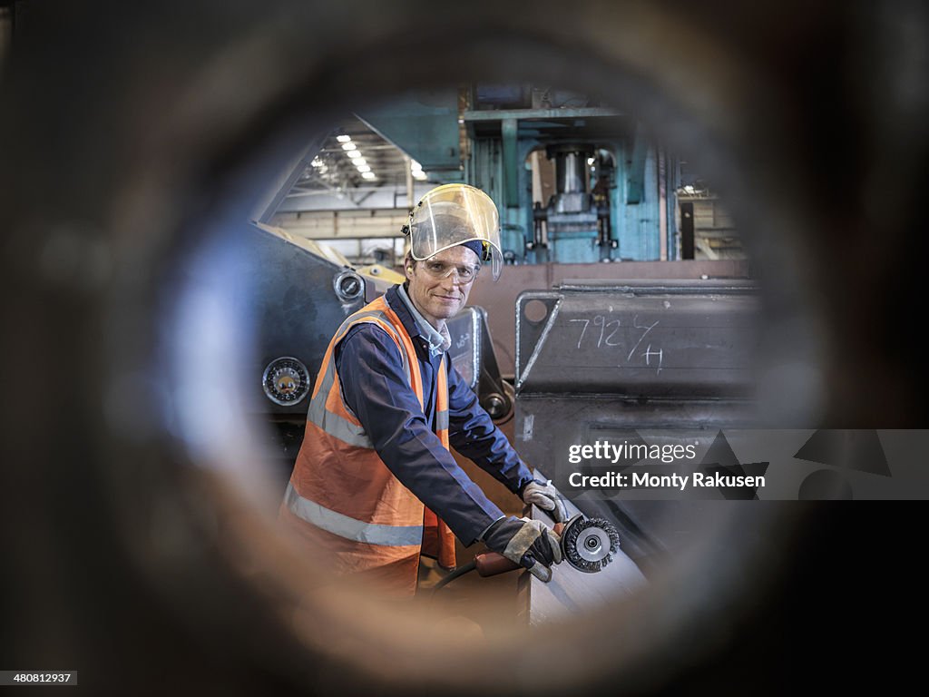 Engineer portrait in factory viewed through hole in steel