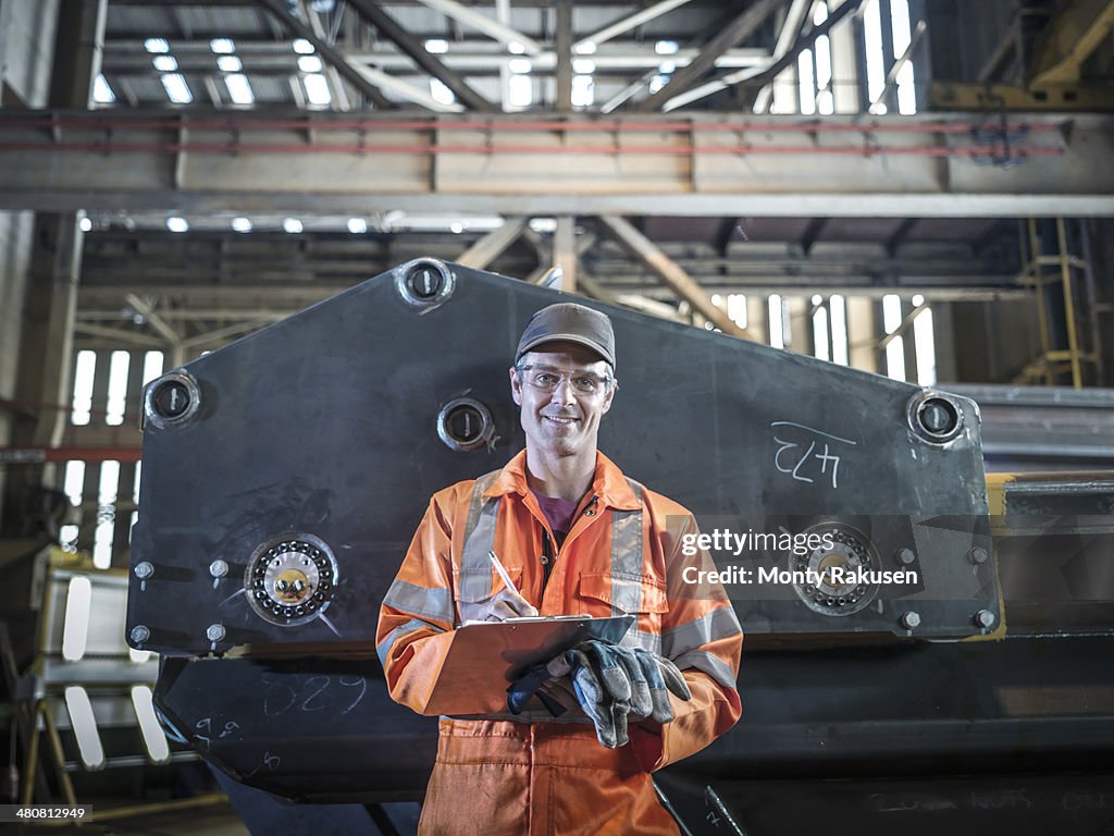 Portrait of engineer holding clipboard in factory
