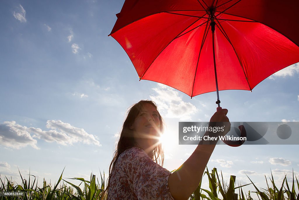 Woman standing holding red umbrella