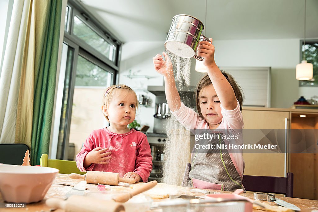 Girl sieving flour in kitchen