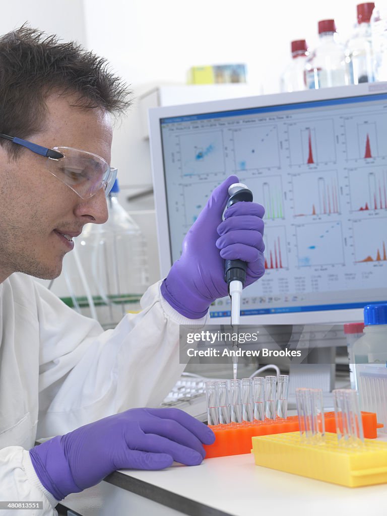 Male scientist pipetting sample into test tubes for analysis of cell population