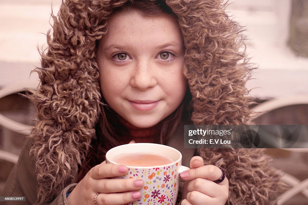 Teenage girl with mug of coffee outdoors