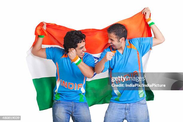 excited young male friends in jerseys cheering while holding indian flag over white background - cricket jersey stock pictures, royalty-free photos & images