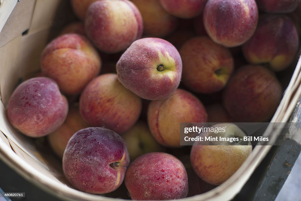 An organic fruit stand. A crate of peaches.