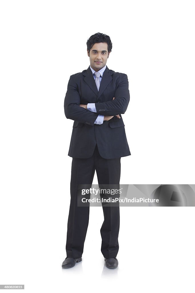 Full length portrait of young businessman standing arms crossed over white background