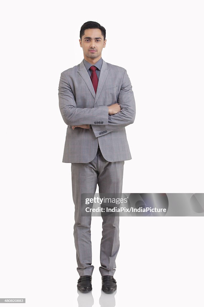 Full length portrait of young businessman standing arms crossed against white background