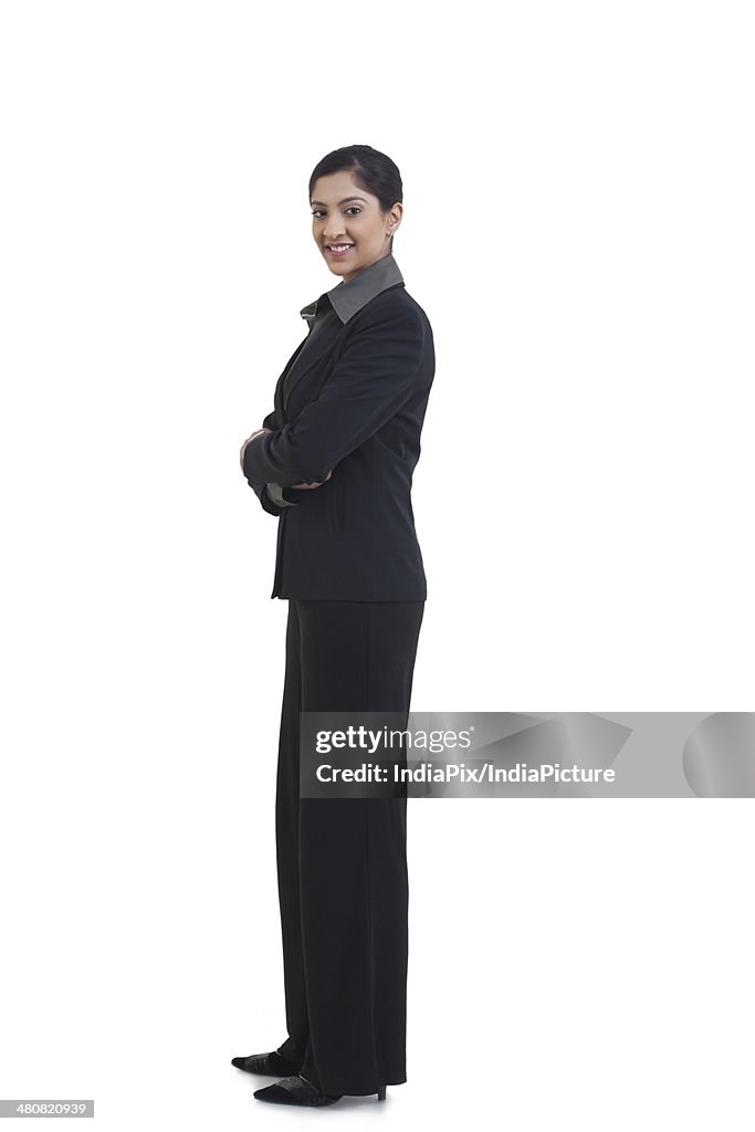 Full length side view of happy businesswoman standing arms crossed against white background